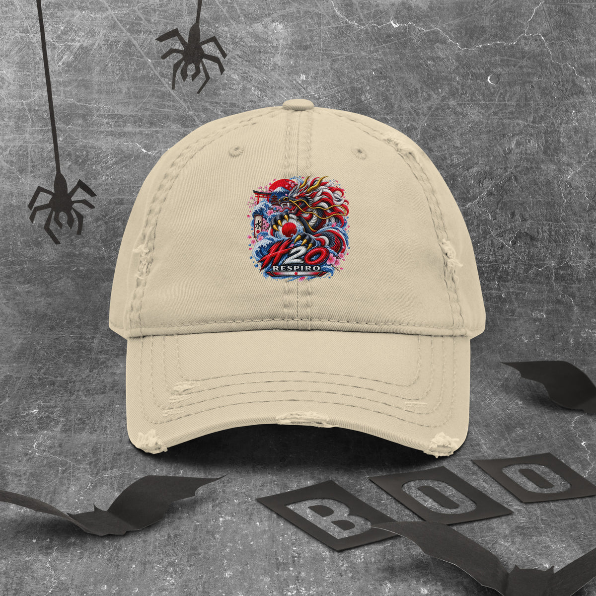 Casquette Dragon Flow – Édition Japon de H2O RESPIRO, en coton beige avec logo coloré brodé au centre, posée sur un fond gris texturé avec des toiles d’araignée décoratives.