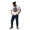 T-shirt unisexe Dragon Flow – Édition États-Unis de H2O Respiro, blanc en coton, porté par un homme avec un grand motif dragon multicolore sur le devant, avec jean et baskets grises.